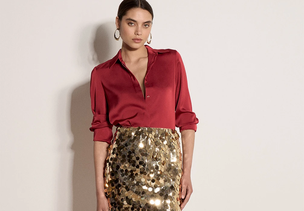 Model wearing a burgundy satin shirt and gold sequin skirt